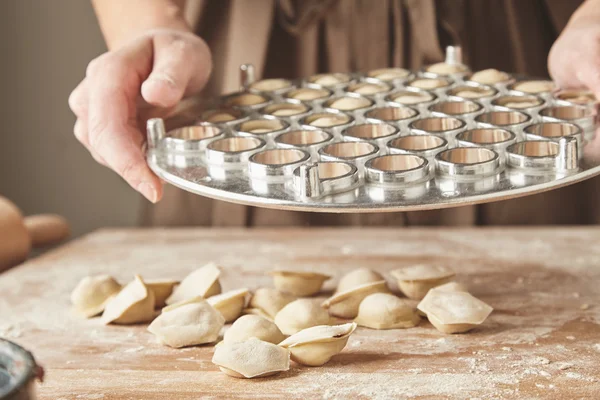 Shaking out ready raviolis from mold — Stock Photo, Image