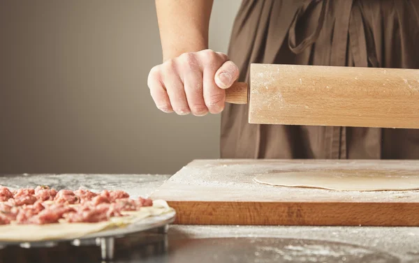 Flatten dough with wooden rolling pin — Stock Photo, Image