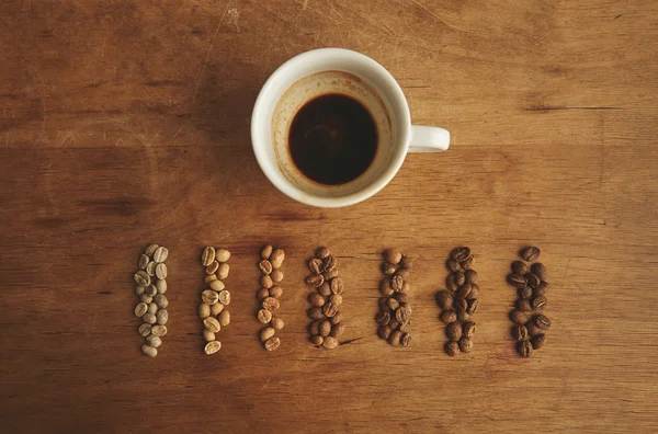 Sorter rostning kaffe nära espressokopp trä bordsskiva vy — Stockfoto