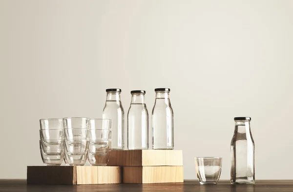 Glasses and bottles with water set on wooden table — Stock Photo, Image