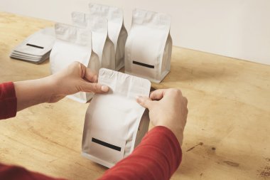 Woman hands seal package for sale above wooden table