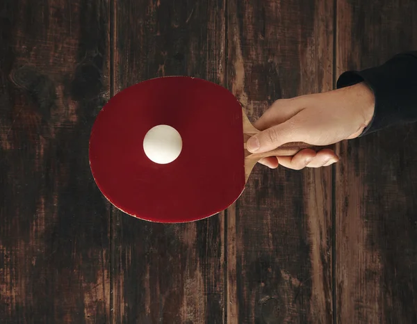 Hand holds one professional rocket above wooden aged table