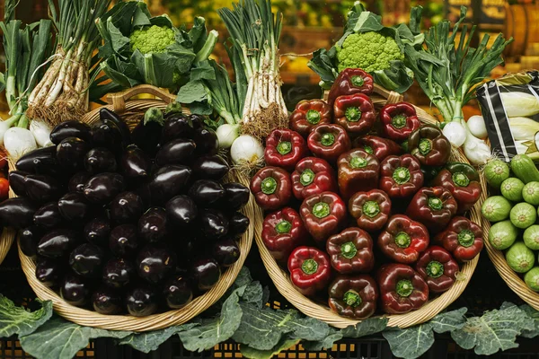 Pimentos e berinjelas frescos em cestos fora da venda no mercado — Fotografia de Stock