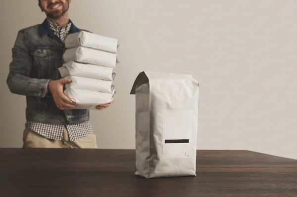 Bigh paquete en blanco presentado en frente desenfocado bolsa cargadora feliz —  Fotos de Stock