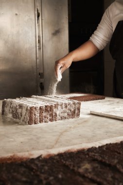 Siyah adam şefi ambalaj önce çikolatalı kek üzerine şeker tozu döker