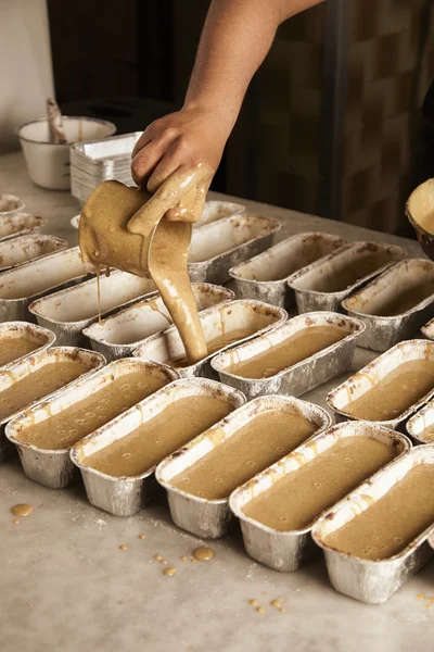 Black man hand pours tasty liquid cake batter from measure cup special metallic foil — Stock Photo, Image