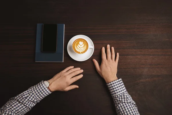 Au centre mains d'homme d'affaires près de tasse de cappuccino — Photo