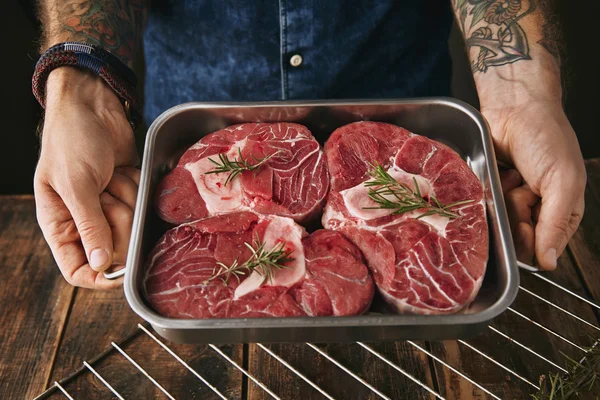 Kézi kézben lévő acél fém festőautomata, három darab friss nyers húst tartalmazó steak — Stock Fotó