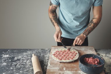 Dövmeli baş adam mantı yemek yapıyor.