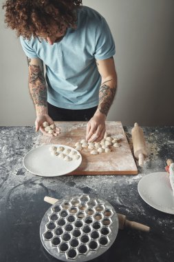 Dövmeli baş adam mantı yemek yapıyor.