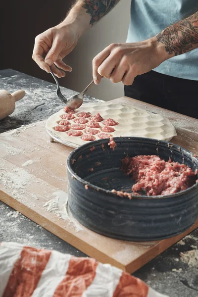 Homem cozinha pelmeni ou bolinhos ou ravioli em molde especial — Fotografia de Stock