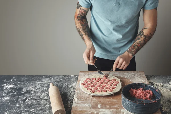 Tattooed chief man cooks pelmeni — Stock Photo, Image