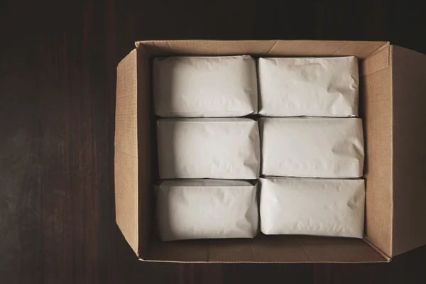 Caja de cartón grande llena de paquetes blancos herméticos en blanco —  Fotos de Stock