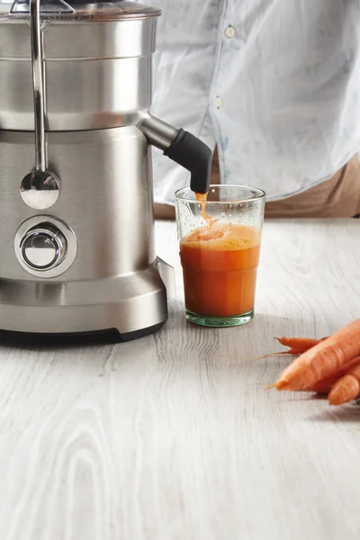 Fresh juice pours from steel professional juicer — Stock Photo, Image