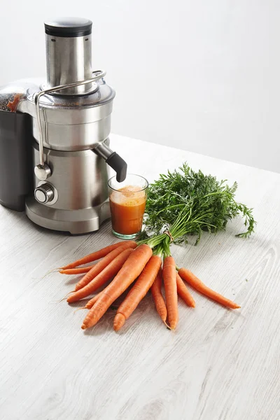Juicer profesional metálico con jugo de zanahorias — Foto de Stock