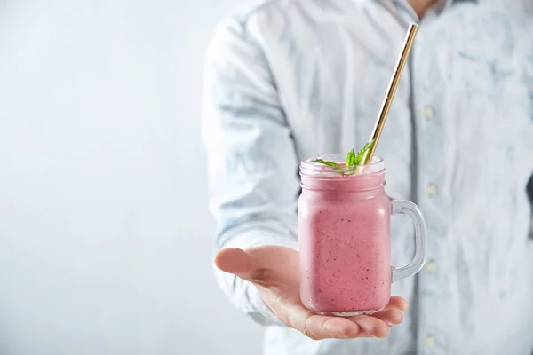 El hombre ofrece frasco rústico con batido de bayas —  Fotos de Stock