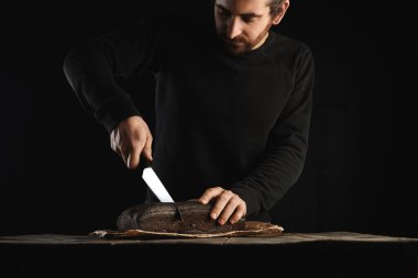 man uses big chief knife to slice bread  clipart