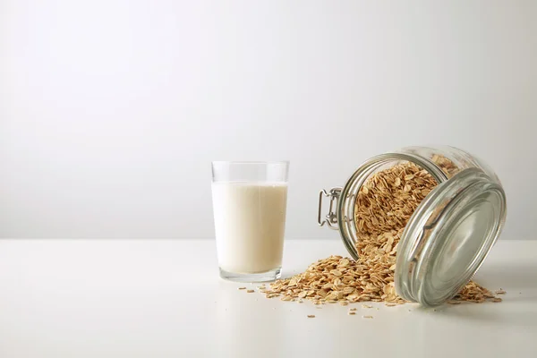 Glass with organic milk  near opened jar with oats — Stock Photo, Image