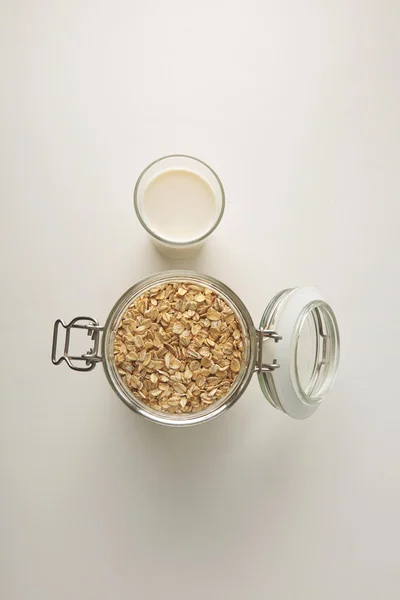 Vaso con leche orgánica cerca del frasco con avena enrollada — Foto de Stock