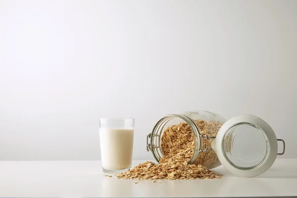 Vidrio transparente con leche cerca de avena laminada —  Fotos de Stock