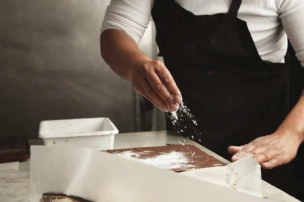 El hombre derrama azúcar en polvo sobre los pasteles — Foto de Stock