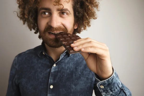 Hombre muerde barra de chocolate al horno — Foto de Stock