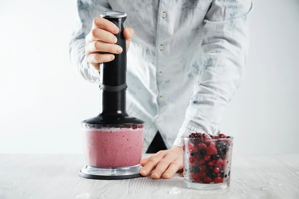 Man blends frozen berries, ice, yogurt — Stock Photo, Image