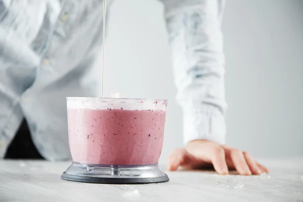 El hombre vierte miel dentro de la licuadora olla con batido —  Fotos de Stock