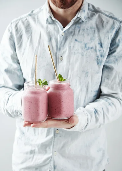 Uomo con due barattoli con frullati di bacche fredde — Foto Stock