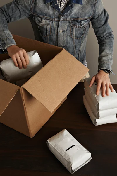 Man puts hermetic packages inside big carton box — Stock Photo, Image