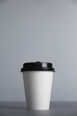 white paper cup with black cap presented in front
