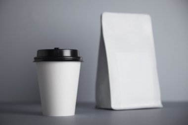 white paper cup with black cap near white bag