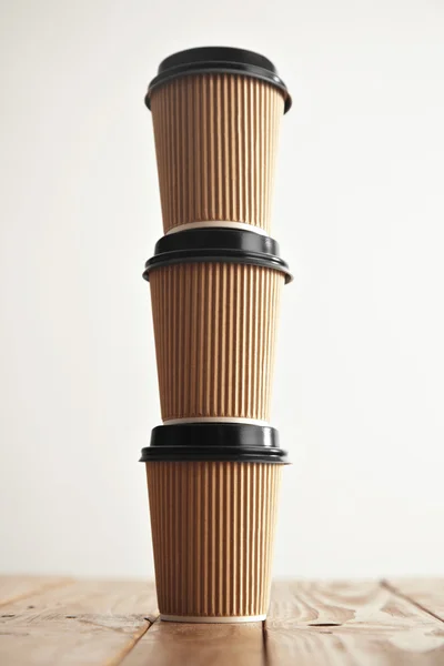 Tres vasos artesanales de papel con tapas negras en columna —  Fotos de Stock