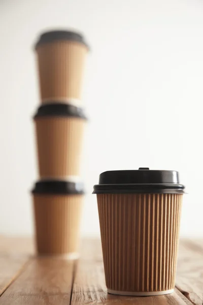 Бумажная чашка перед тремя чашками, стоящими в колонке — стоковое фото