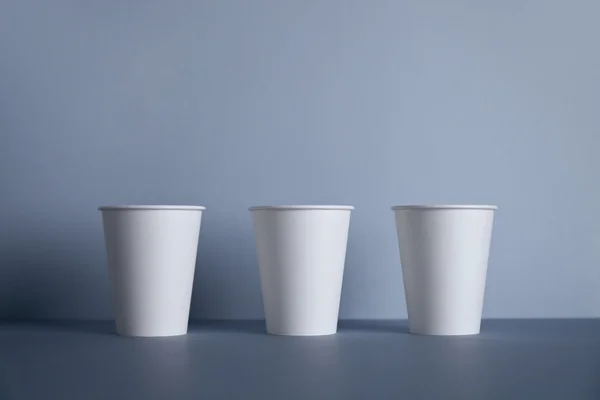 Три белые бумажные чашки в ряд — стоковое фото