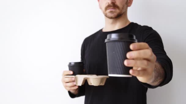 Homme en noir présente tasse en papier sur la caméra — Video