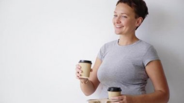 woman in t-shirt enjoys drink from paper cup