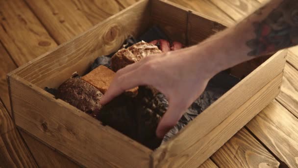 Рука кладет различные хлеба в коробку — стоковое видео