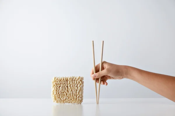 Hand with chopsticks near noodles