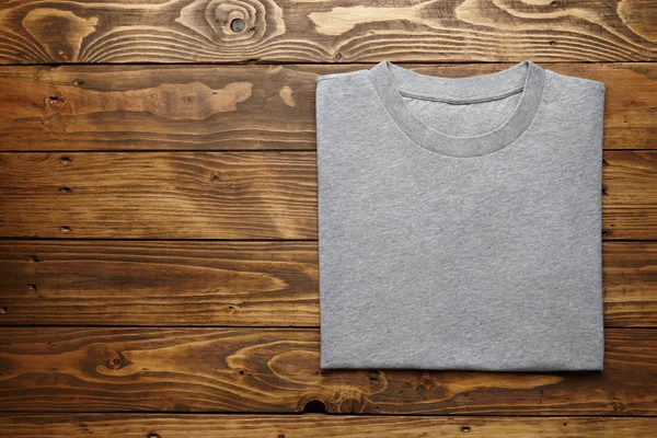 Camiseta gris en blanco sobre mesa de madera —  Fotos de Stock