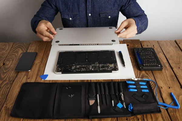 man opens backside top-case cover of computer