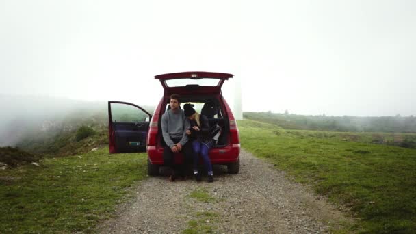 Os viajantes sentam-se na bota aberta do carro — Vídeo de Stock