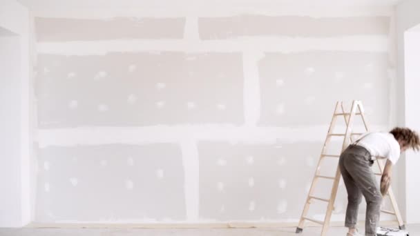 Man brengt houten trappen en schildert muur — Stockvideo