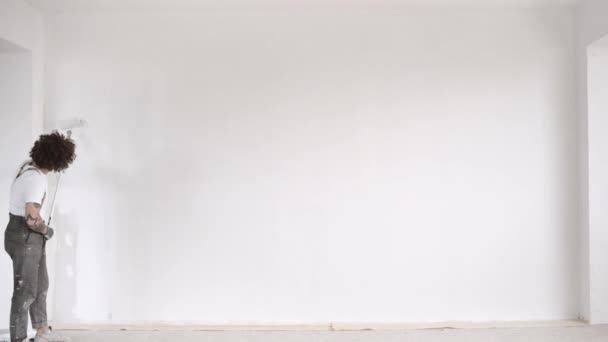 Mann bemalt Teil einer großen Wand aus Gipskartonplatten — Stockvideo