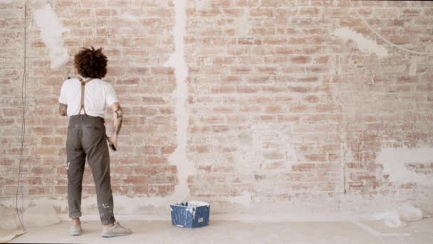 Hombre comienza a pintar pared de ladrillo rojo — Vídeos de Stock