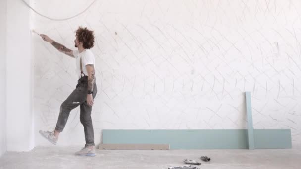 Člověk maluje zeď s jednou nohní squaty — Stock video