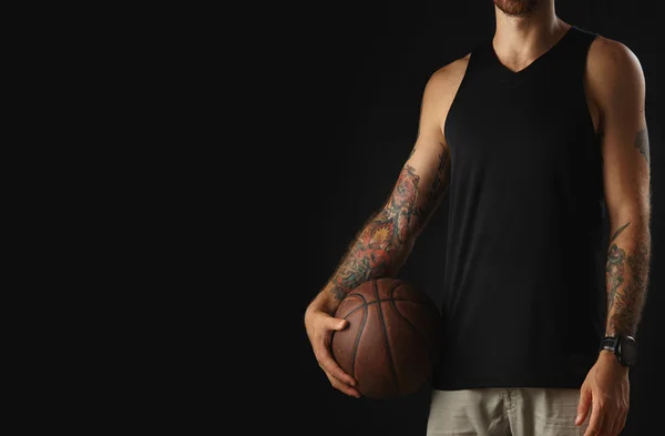Brutal atleta tatuado sostiene pelota de baloncesto de cuero — Foto de Stock