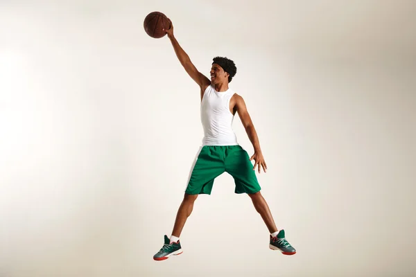 Sonriente hombre negro alcanzando alto para el baloncesto — Foto de Stock