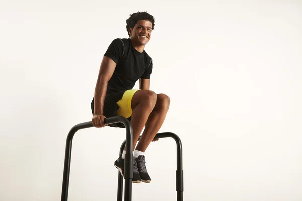 Сильный молодой черный спортсмен встает на колени на параллельных брусьях — стоковое фото