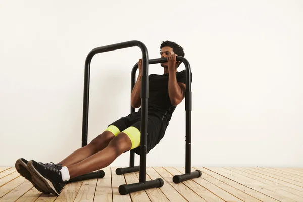 Молодий чорний спортсмен робить рядки ваги тіла на брусках — стокове фото
